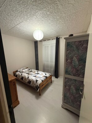A bedroom with a bed, a wardrobe, and a ceiling with a textured pattern.