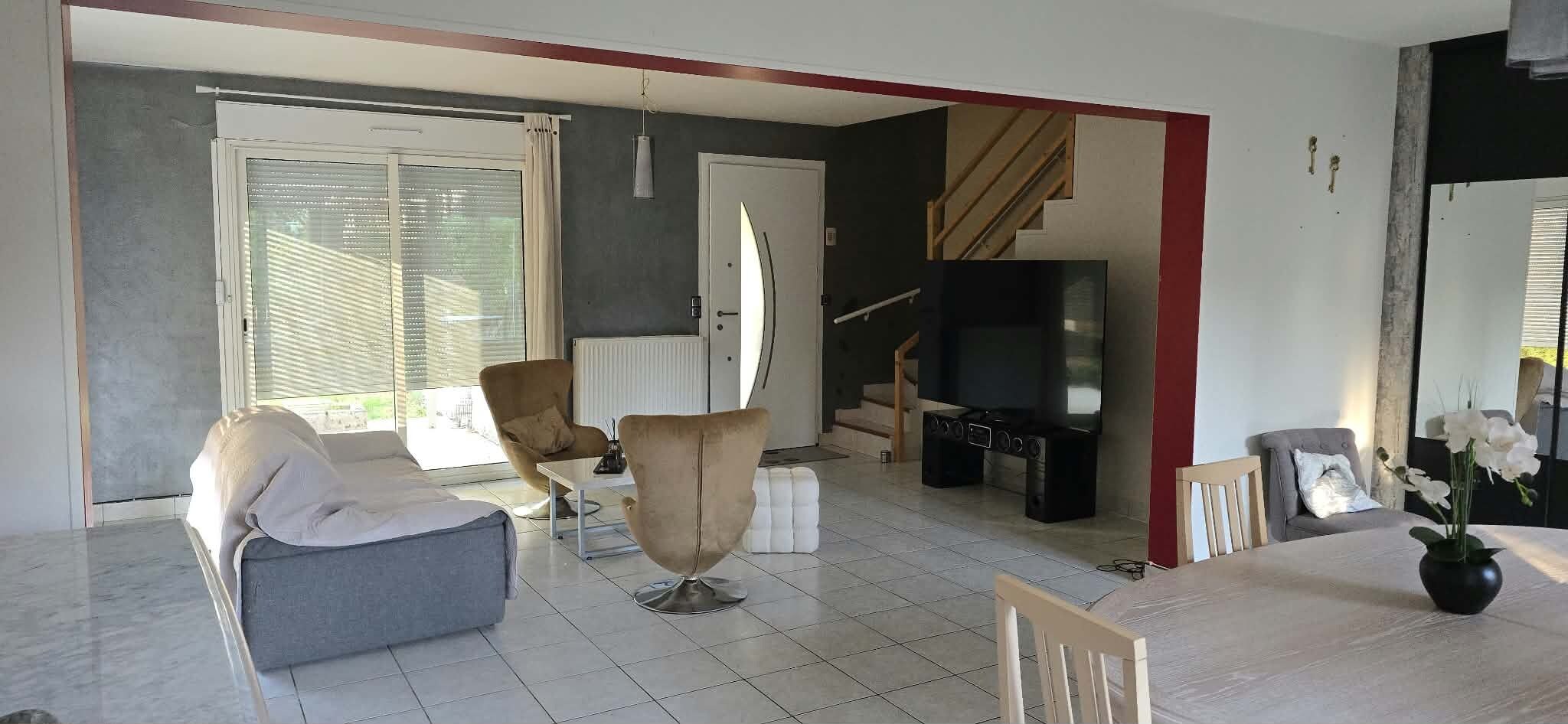 A living room with a sofa, armchair, and a dining table with chairs.