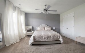 A bedroom with a bed, a ceiling fan, a nightstand, a chair, and a wardrobe. - Luxury 1BR Retreat Near Uptown, Speedways & UNCC (Charlotte)