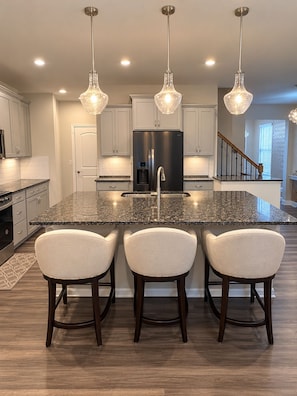 A modern kitchen with a central island, stainless steel appliances, and pendant lighting. - Luxury 1BR Retreat Near Uptown, Speedways & UNCC (Charlotte)