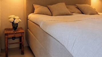Een slaapkamer met een groot bed, twee bedlampjes en een klein tafeltje met een bloevas.