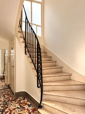 Eine Treppe mit einer schwarzen Metallreling und beigefarbenen Teppichstufen.