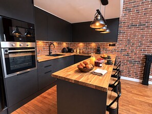 Eine moderne Küche mit Backsteinwand, Holztischplatte und schwarzen Schränken.