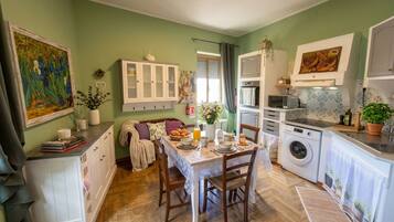 A compact kitchen with a dining table, chairs, a washing machine, and cabinets.