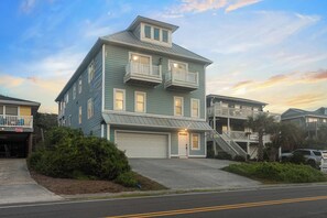 A two-story residential building with a garage, a balcony on the second floor, and a staircase leading to an upper level. - Walk to Beach | Hot Tub | 9BR/5BA | Sleeps 20+ (Surf City)