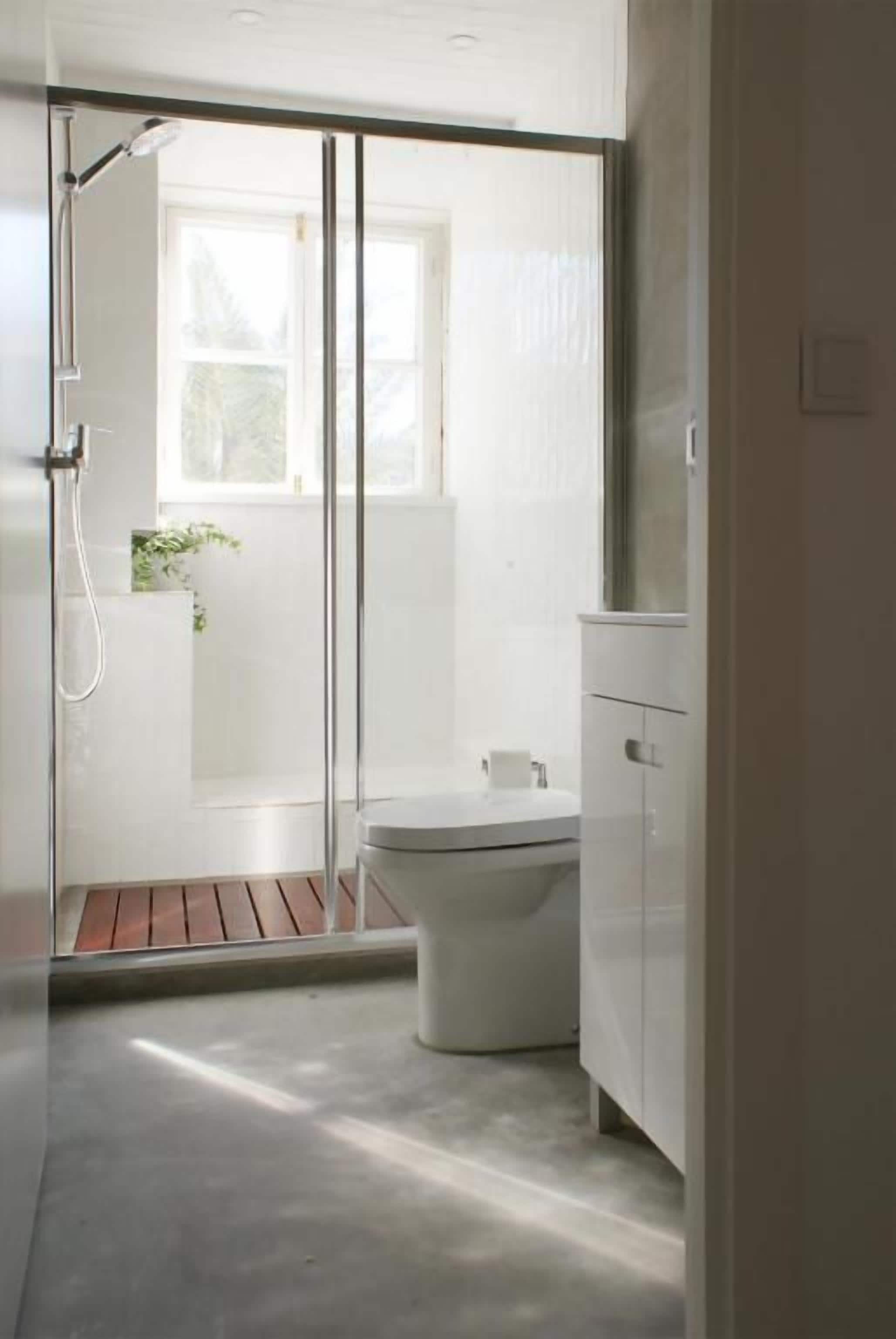 Un baño moderno con ducha, inodoro y ventana que proporciona luz natural.