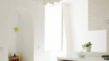 Una cocina moderna con armarios blancos, una lámpara de papel con forma de flor colgante y una pequeña planta en maceta sobre la encimera.