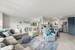 Ein modernes Wohnzimmer mit Ecksofa, Essbereich und einer Küche mit Edelstahlgeräten.