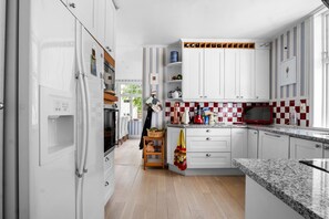 Eine moderne Küche mit weißen Schränken, einer rot-weißen Schachbrett-Spritzschutzwand und einem Edelstahl-Kühlschrank.