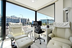 A modern office space with a desk, two chairs, and a large window offering a city view. - Station Square Stay for 4 (Blankenberge)