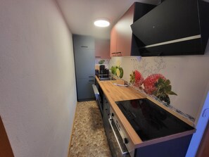 Una cocina estrecha con encimera de madera, estufa negra y un microondas.