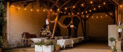 An outdoor dining area with tables, string lights, and potted plants.