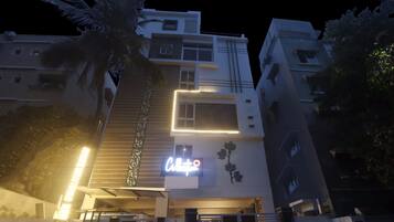 Um edifício moderno com vários andares e uma placa iluminada bem visível na fachada.