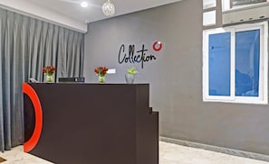 A reception desk with a nameplate, a wall with a sign reading 'Collection', and a window with blinds. - Super Townhouse RCC Pristine (Hyderabad)