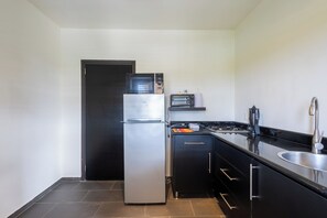 A compact kitchen with a refrigerator, microwave, stove, and sink. - Casa Pasha - Apartment Tiara - Jan Thiel (Jan Thiel)