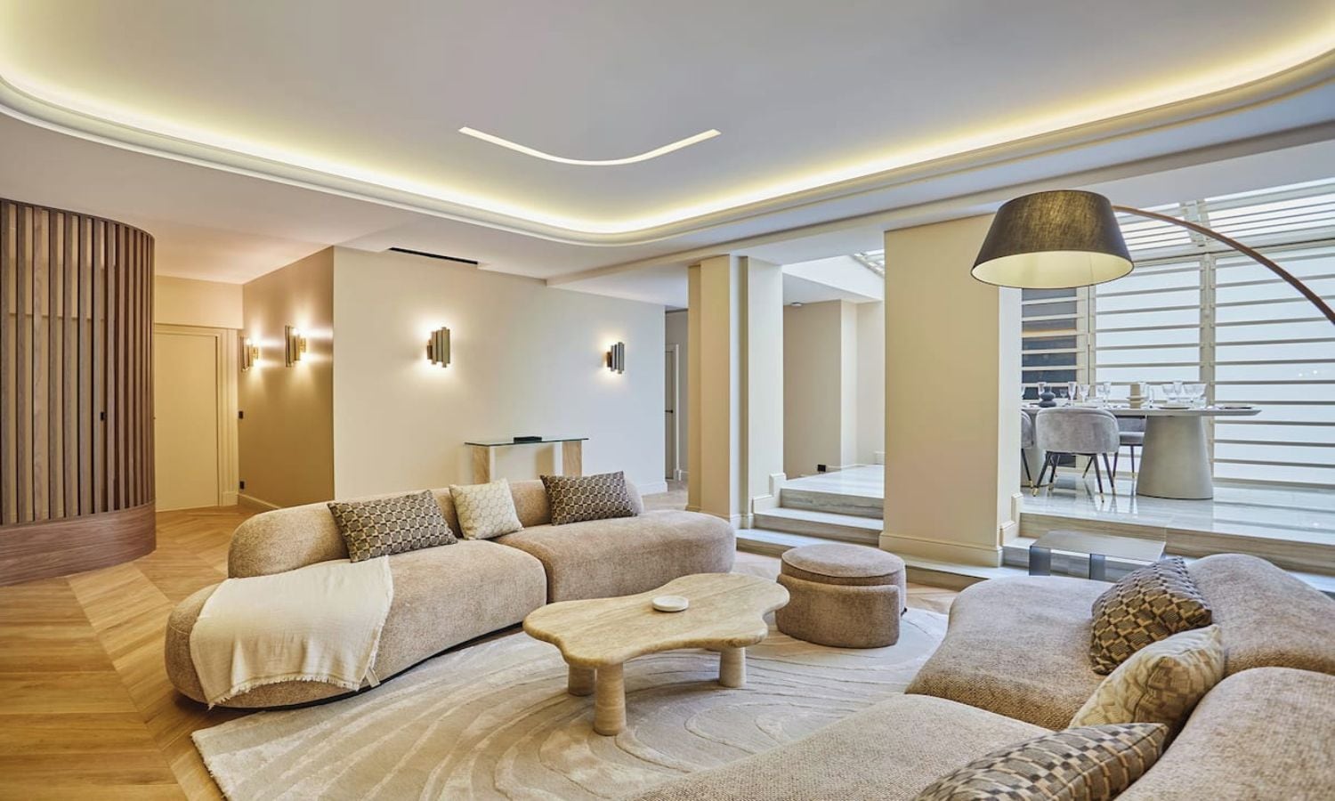 A modern living room with a sectional sofa, a coffee table, and a dining area with a table and chairs.