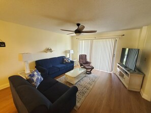 A living room with a sofa, armchair, coffee table, and a television. - Ocean Village Club I25 2 Bedroom Condo (St. Augustine)
