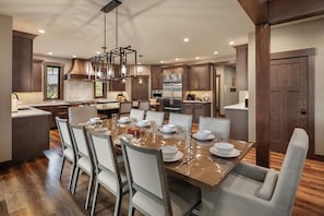A modern kitchen with a central island, stainless steel appliances, and a dining area with white chairs. - Private Pool! Stunning View Overlooking Hole #4 on the Rope Rider Golf Course (Cle Elum)