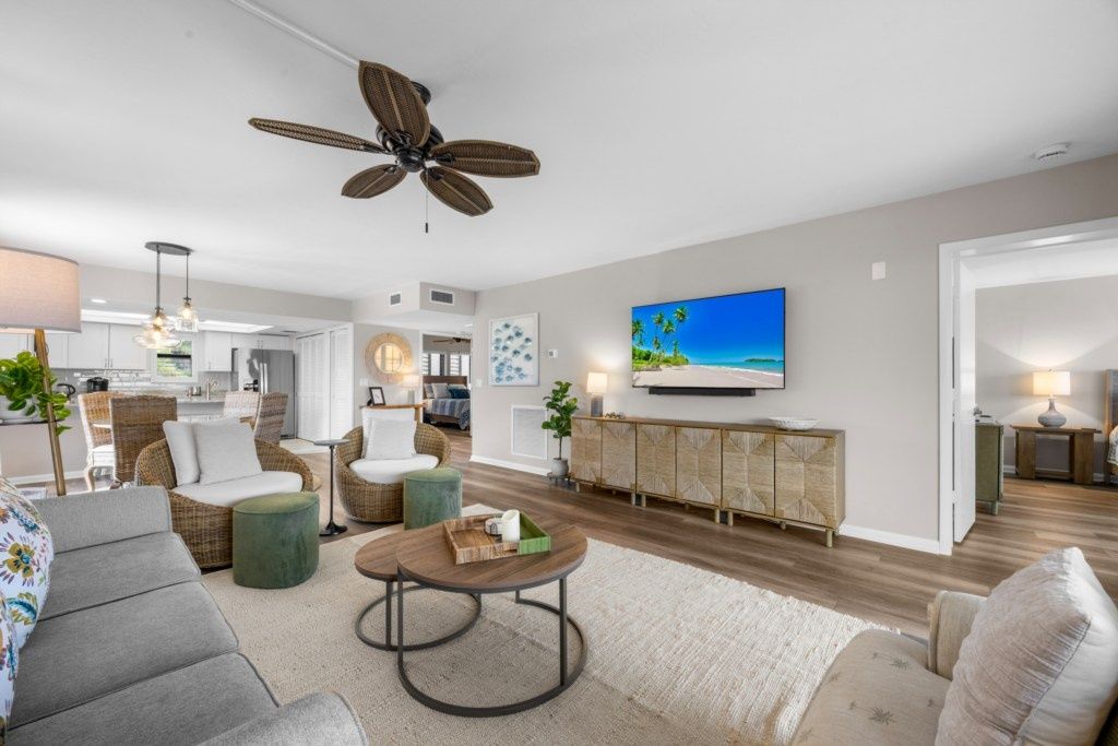 A modern living room with a ceiling fan, a flat-screen TV, and a dining area.