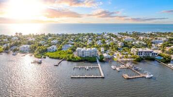 An aerial view of a coastal town with a marina, residential buildings, and a large hotel with a modern design.