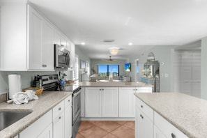 A kitchen with white cabinets, a microwave, and a large island with a sink. - Captiva Shores 6a 2 Bedroom Condo (Captiva)