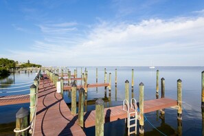 Eine hölzerne Pier, die sich in ruhiges Wasser erstreckt, mit blauem Himmel darüber.