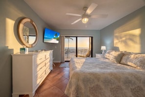 Un dormitorio con cama, cómoda, televisor y balcón con vistas.