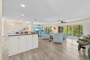 Eine geräumige Küche mit Kochinsel, ein Essbereich mit Tisch und Stühlen sowie ein Wohnzimmer mit Sofas.
