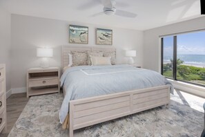 A bedroom with a bed, nightstands, and a view of the ocean. - Pelicans Roost 303 2 Bedroom Condo (Sanibel)