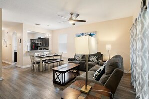 A modern living room with a dining area, a ceiling fan, and a kitchen in the background. - Lms744 4 Bedroom Home (Davenport)