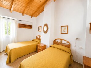 Ein Zimmer mit zwei Betten, Holz-Kopfteilen, einem Holzregal, einem Spiegel und einer Wandsteckdose.