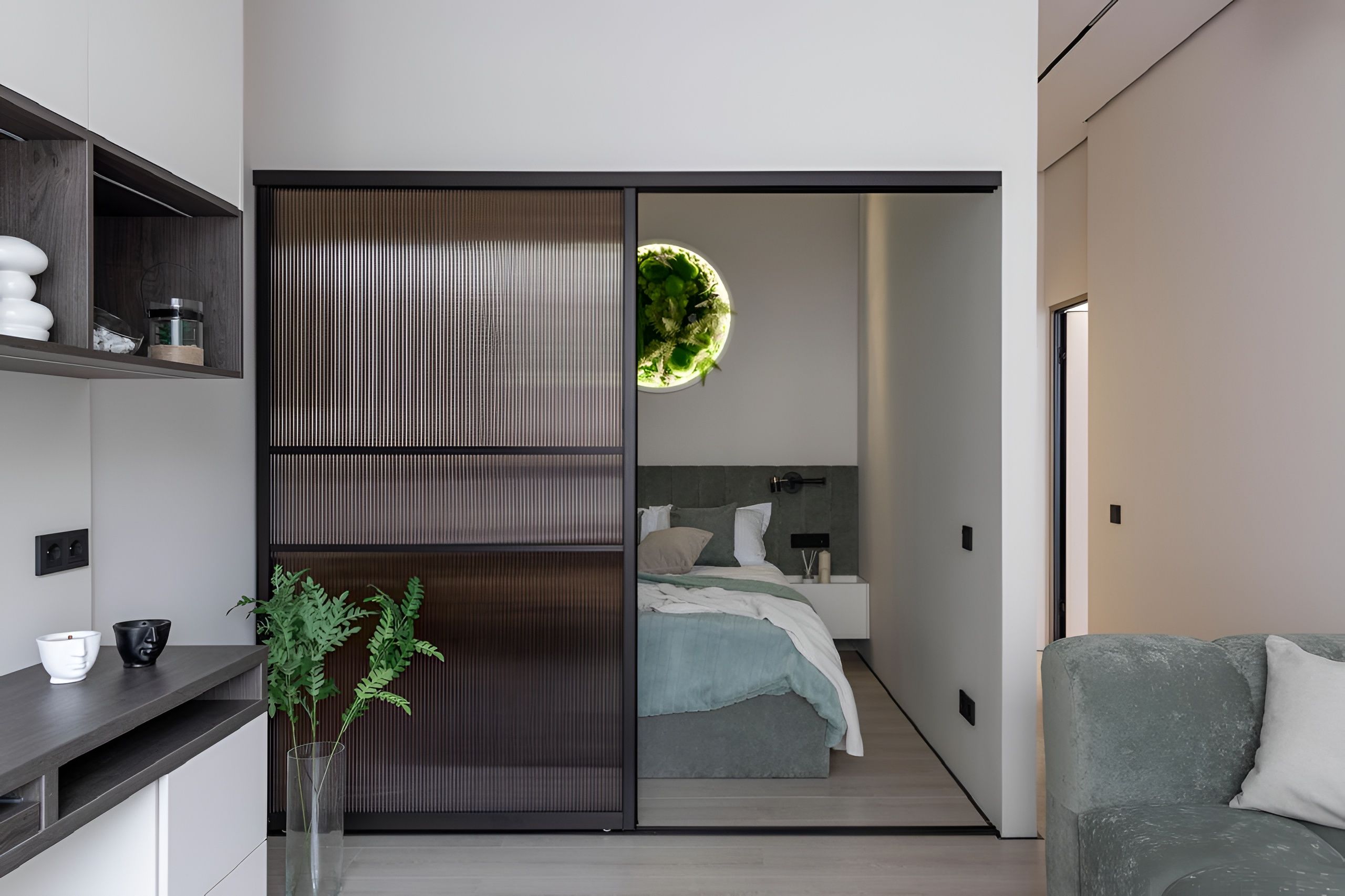 A modern bedroom with a bed, bedside table, and a plant.