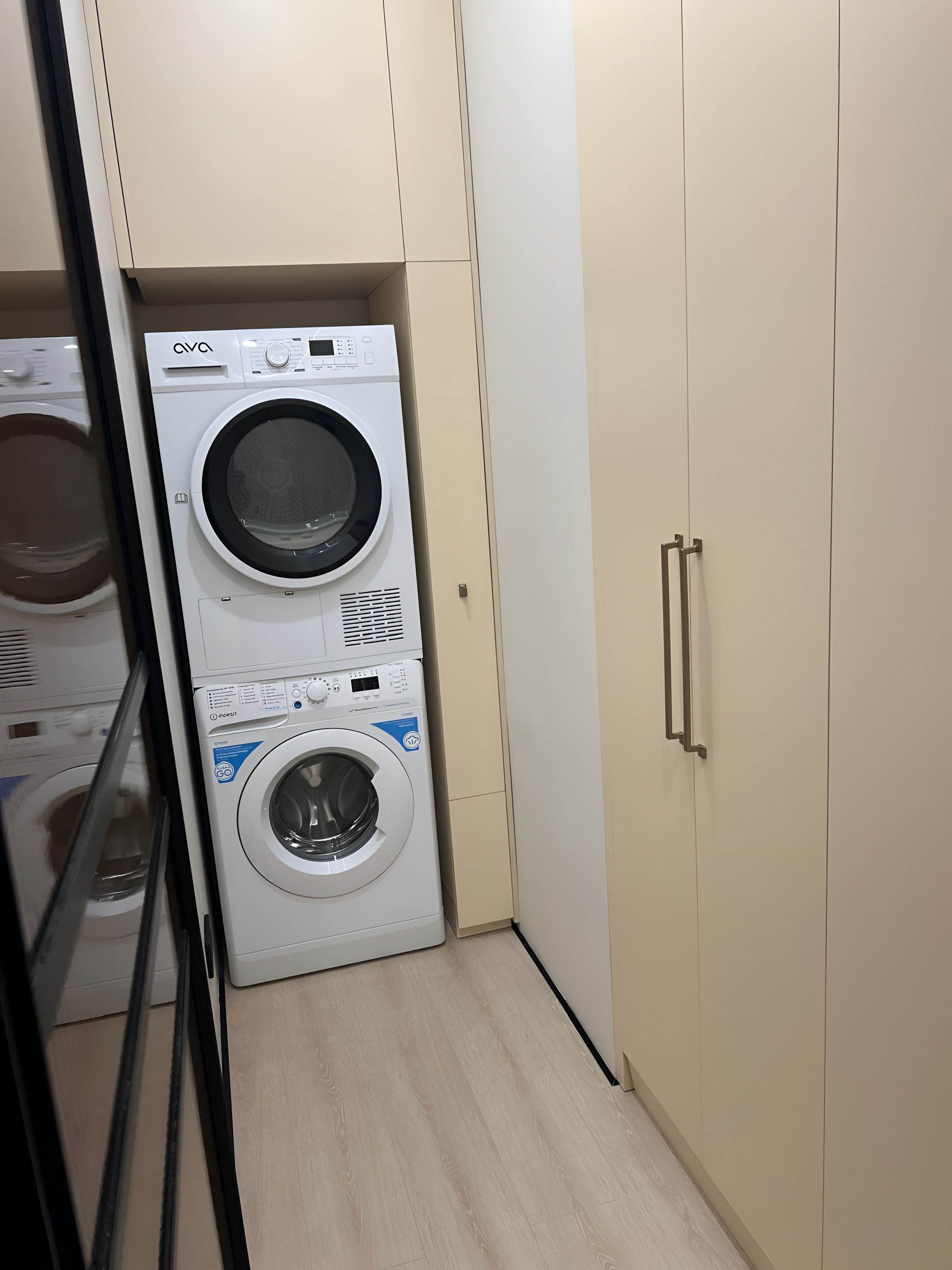 Un lavadero con dos lavadoras apiladas, un armario y una puerta.