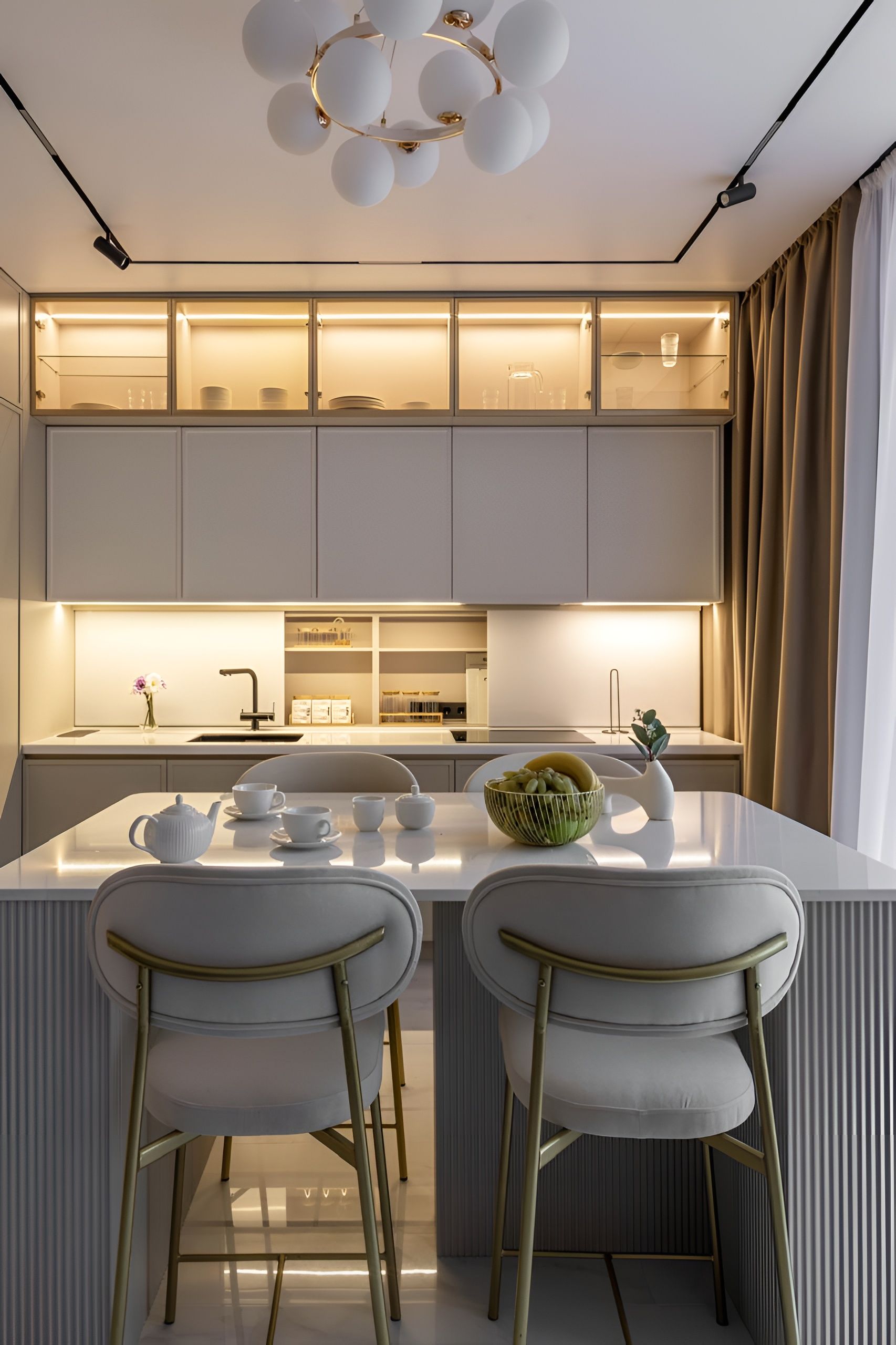 A modern kitchen with a central island, two chairs, and a chandelier.