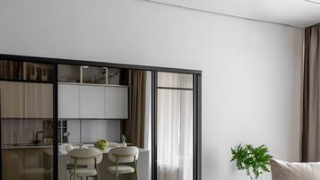 Un soggiorno moderno con un tavolino in vetro, un divano e una zona pranzo con una cucina sullo sfondo.
