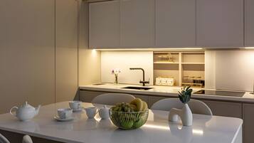 Een moderne keuken met een centraal eiland, witte kasten en een ingebouwde oven.