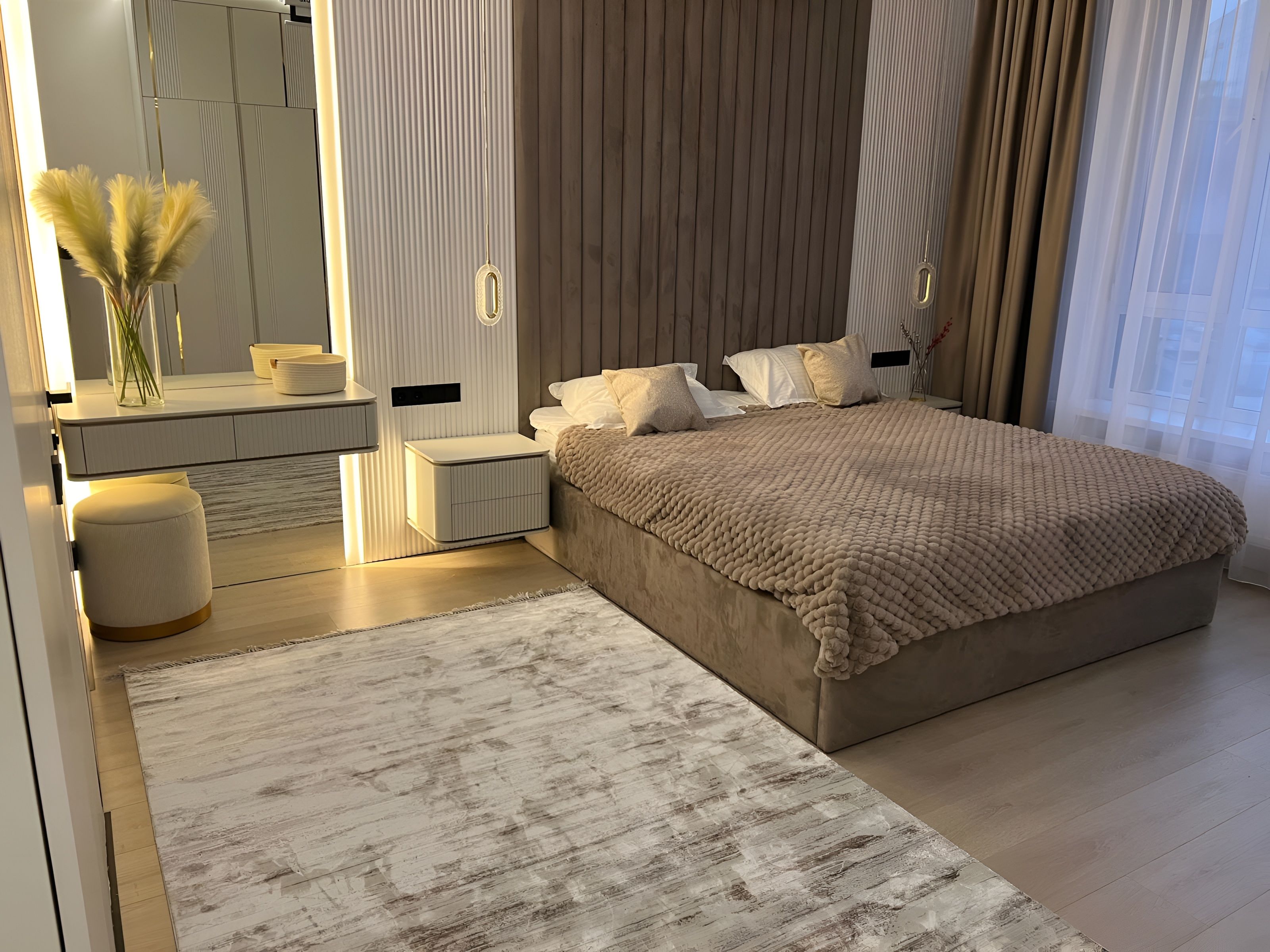 Een moderne slaapkamer met een groot bed, nachtkastjes, een spiegel en een decoratieve vaas.