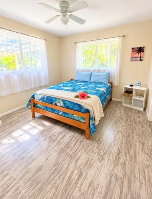 A bedroom with a bed, a ceiling fan, a window with curtains, and a wall shelf.