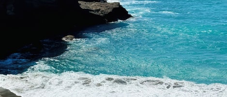 Paesaggio costiero con una scogliera rocciosa e una spiaggia di sabbia.
