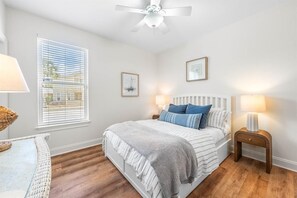 A bedroom with a bed, bedside lamps, a ceiling fan, and a window with blinds. - Key Lime Cottage (Santa Rosa Beach)