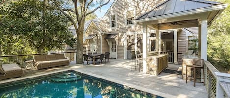 Ein Haus mit Pool, Sitzgelegenheiten im Freien und einer überdachten Terrasse.