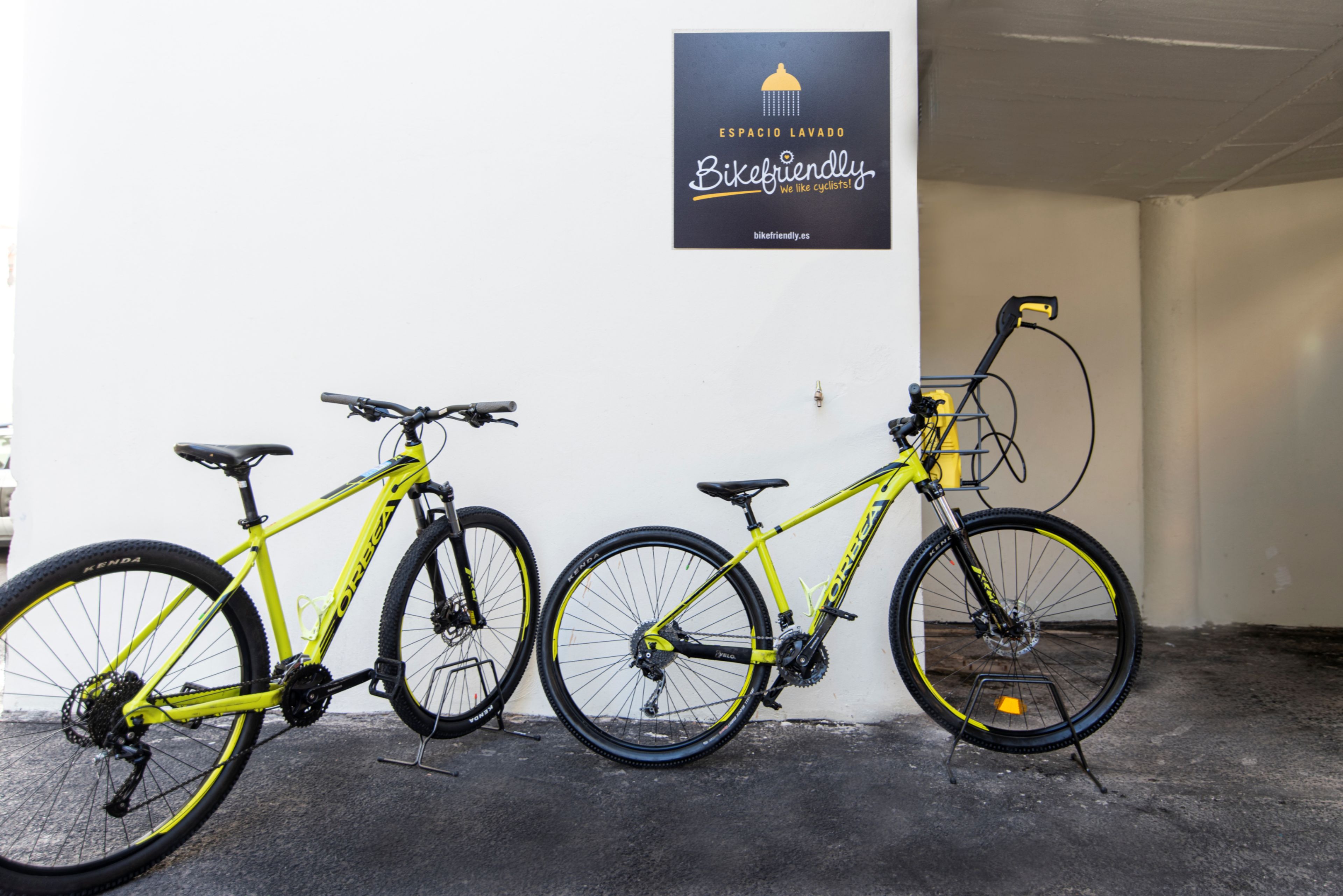 Dos bicicletas estacionadas junto a una pared con un letrero encima.