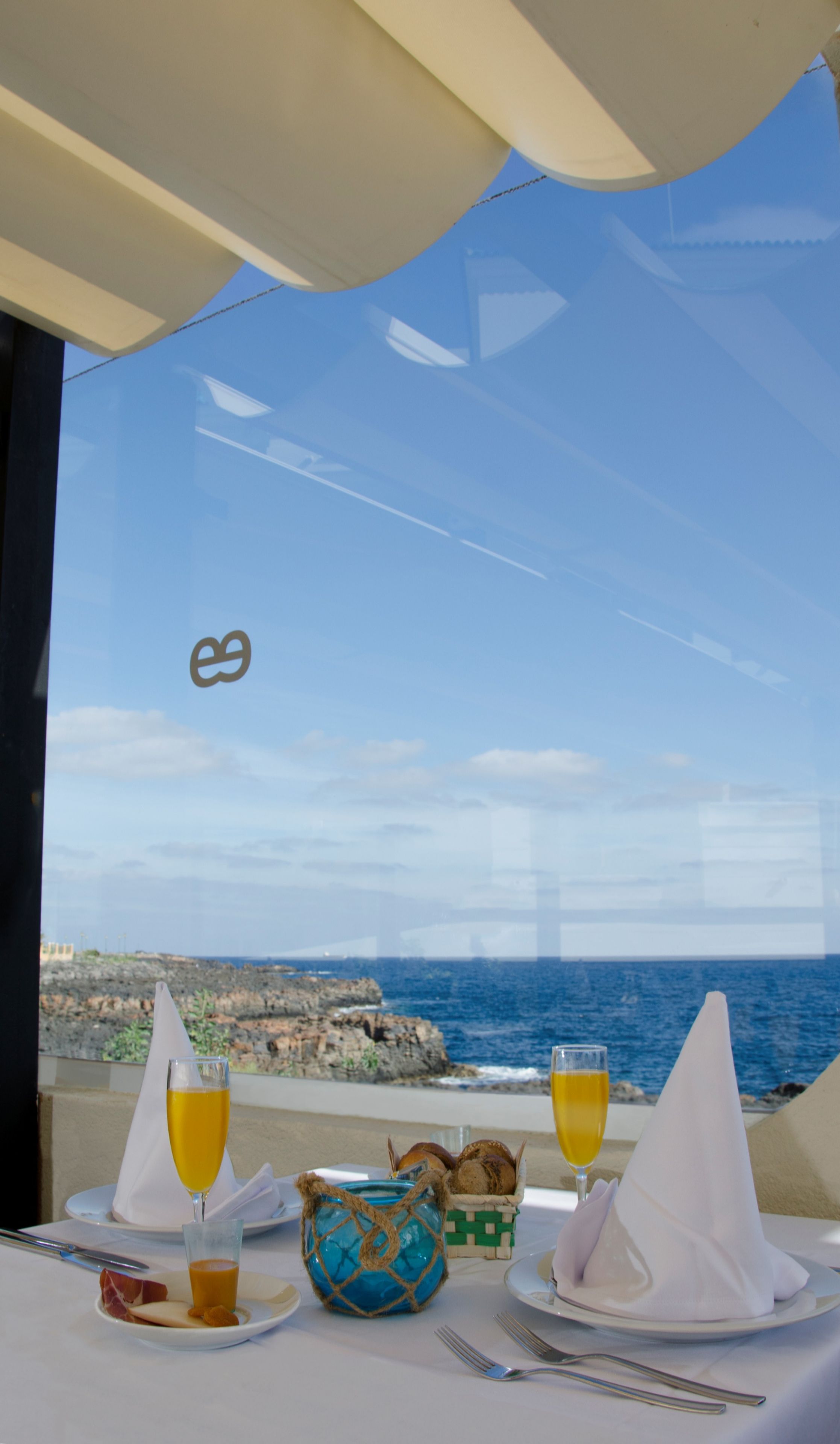 Una mesa para dos con vista al mar y a la costa rocosa.