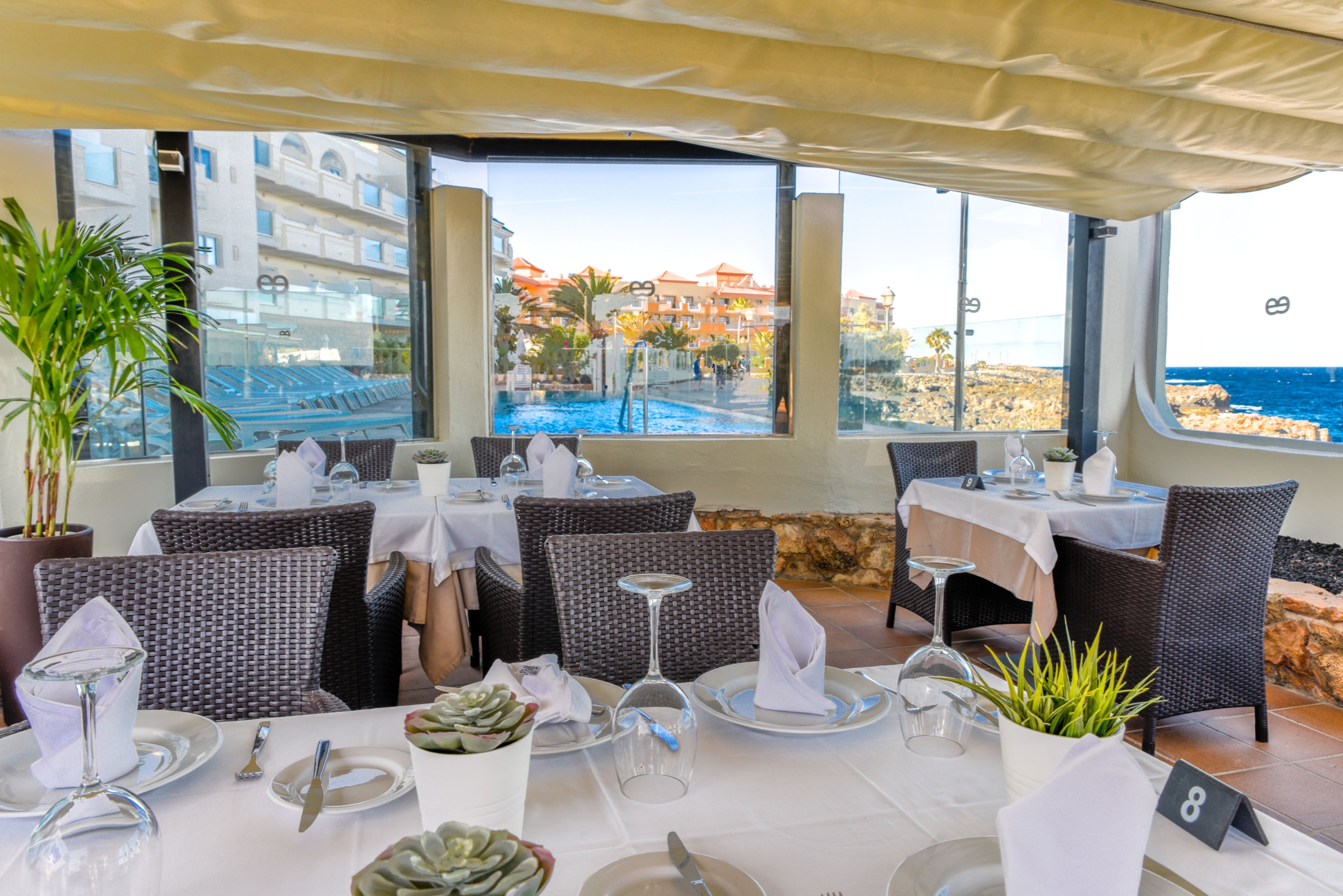 Een restaurant met terras dat uitzicht biedt op een zwembad en de kust.
