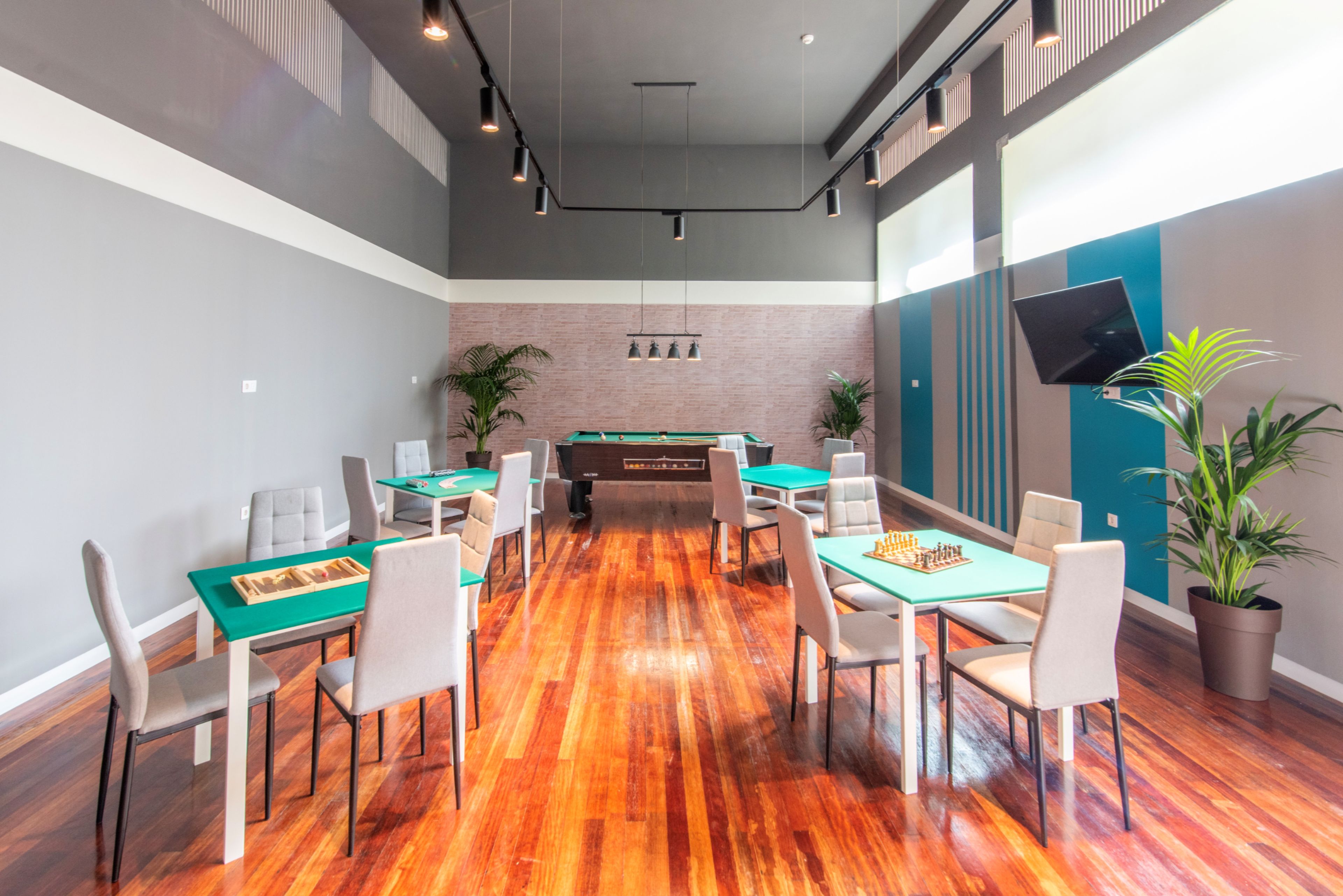 A room with a pool table, multiple chairs, and a television mounted on the wall.