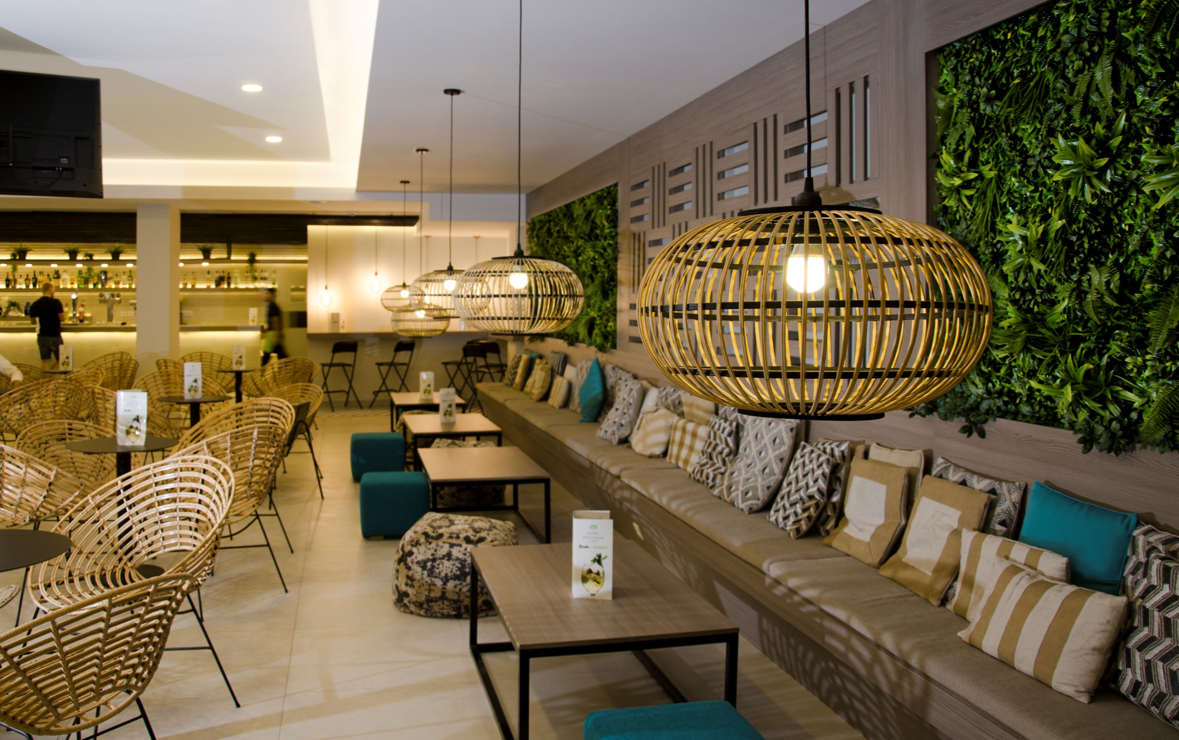 A modern interior with wicker furniture, a long sofa with cushions, and hanging wicker lamps.