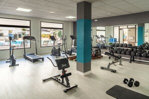 A gym with various exercise equipment, including treadmills, stationary bikes, and free weights.