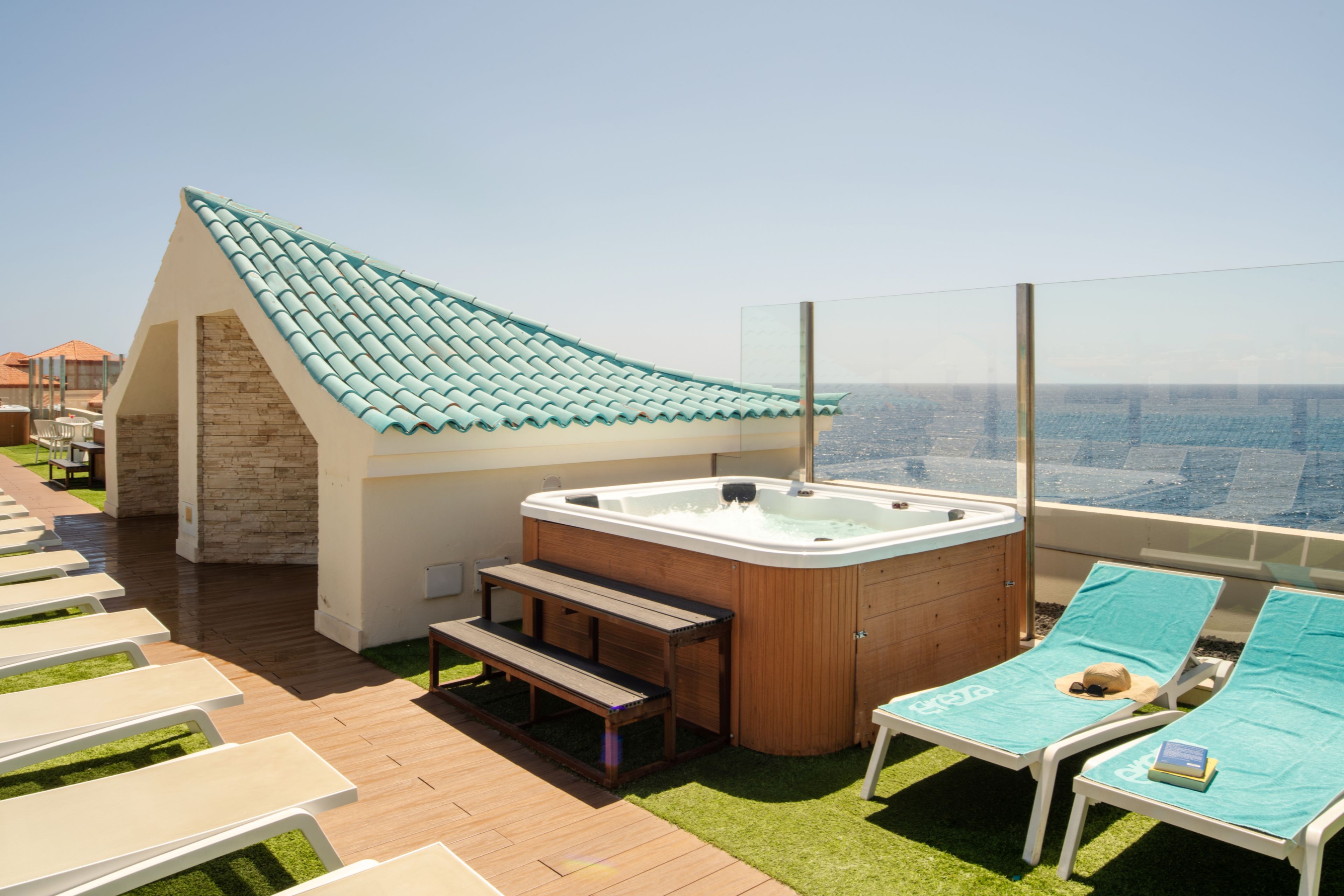 Una terraza en la azotea con un jacuzzi, sillones de descanso y vistas a la ciudad.