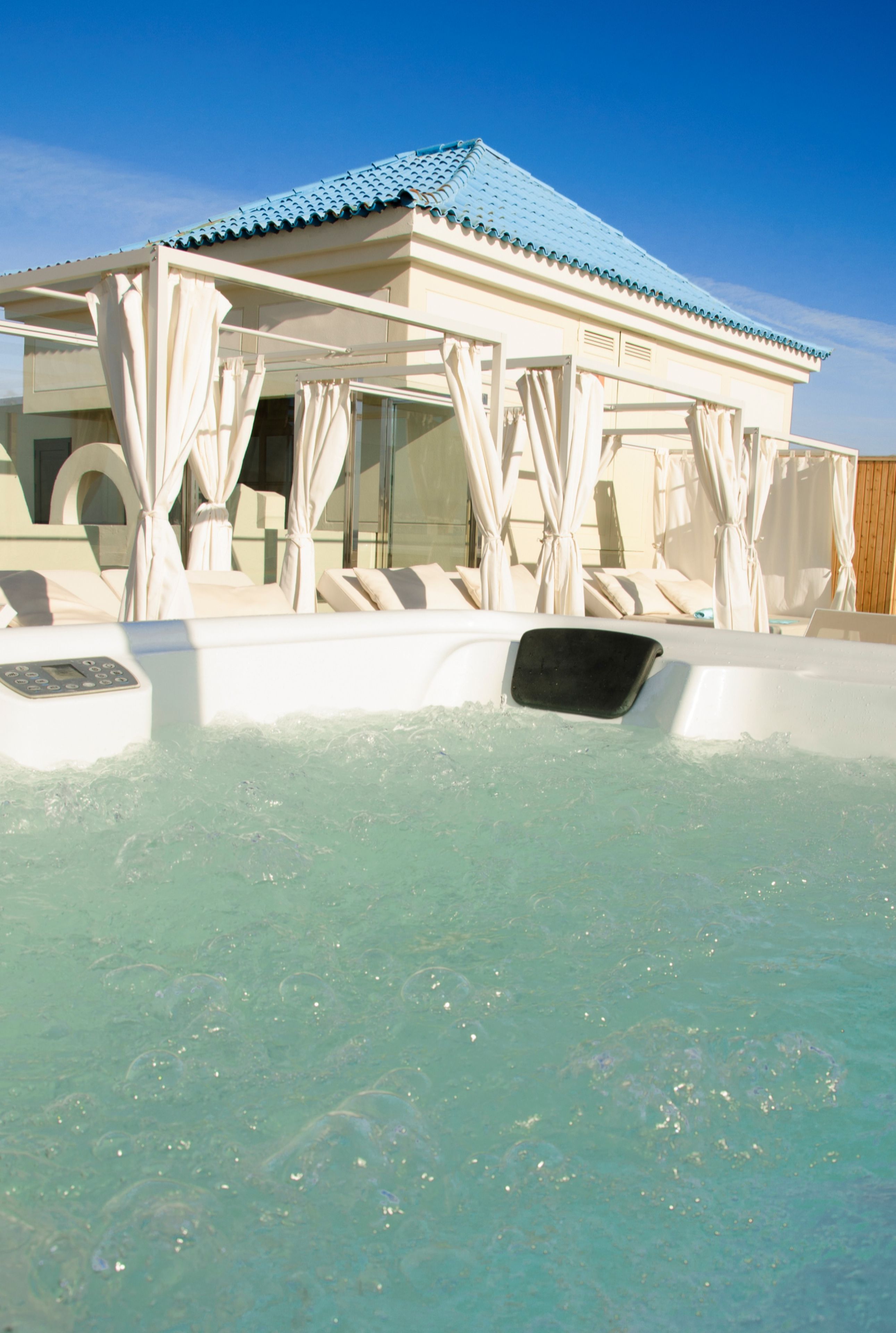Un espace piscine doté d’un coin salon abrité et surplombé d’un ciel d’un bleu éclatant.