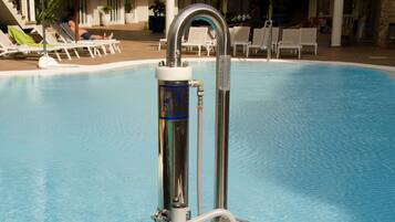 A pool with a lifeguard chair and a metal pole.